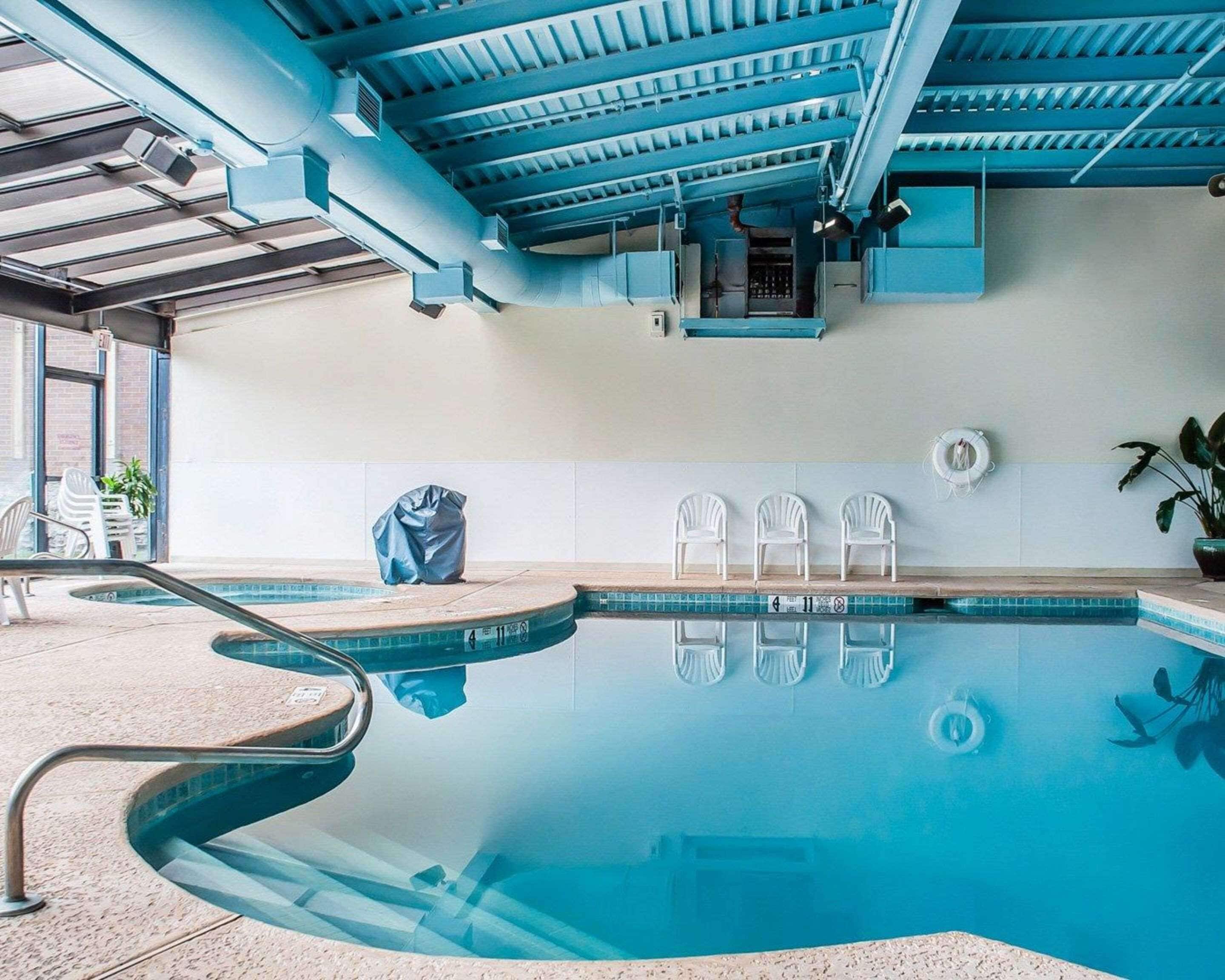 An indoor swimming pool with clear water, a tiled floor, and a blue ceiling.