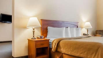 Ein Hotelzimmer mit einem Holz-Kopfteil, zwei Nachttischen mit Lampen, einem Bett mit brauner Bettdecke und einem an der Wand befestigten Flachbildfernseher.