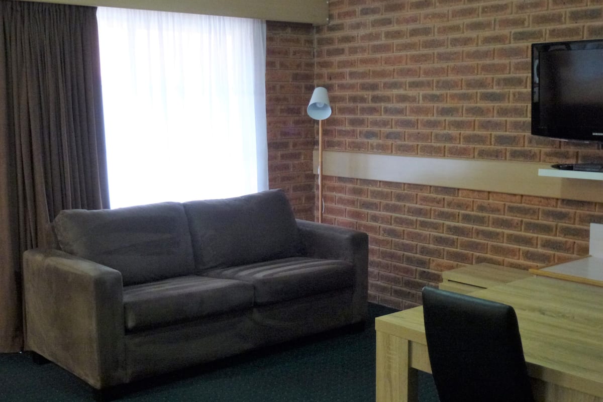 A room with a brick wall, a sofa, a table, and a television.