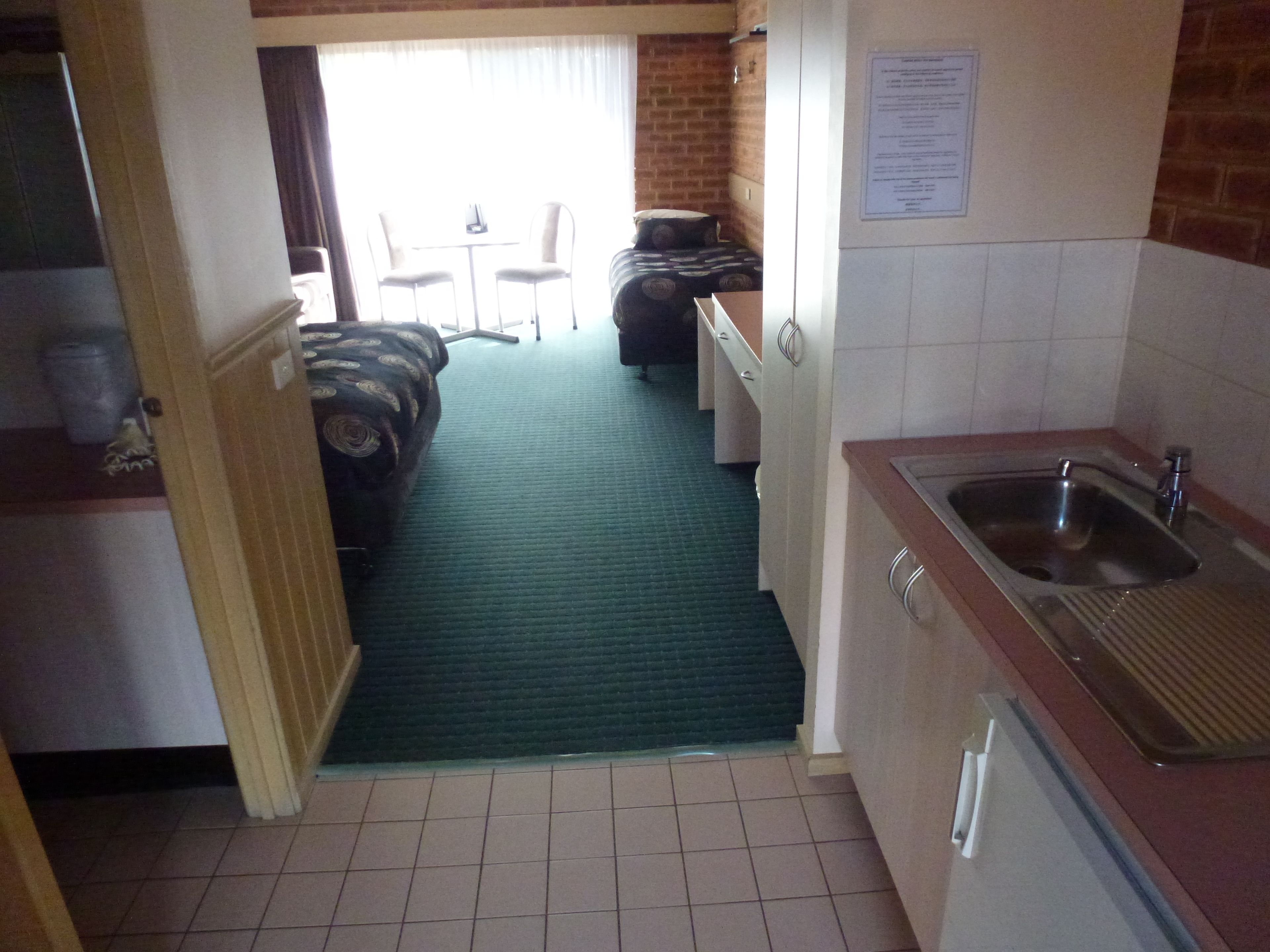 Habitación de hotel compacta con kitchenette, un pequeño comedor y vistas al exterior.
