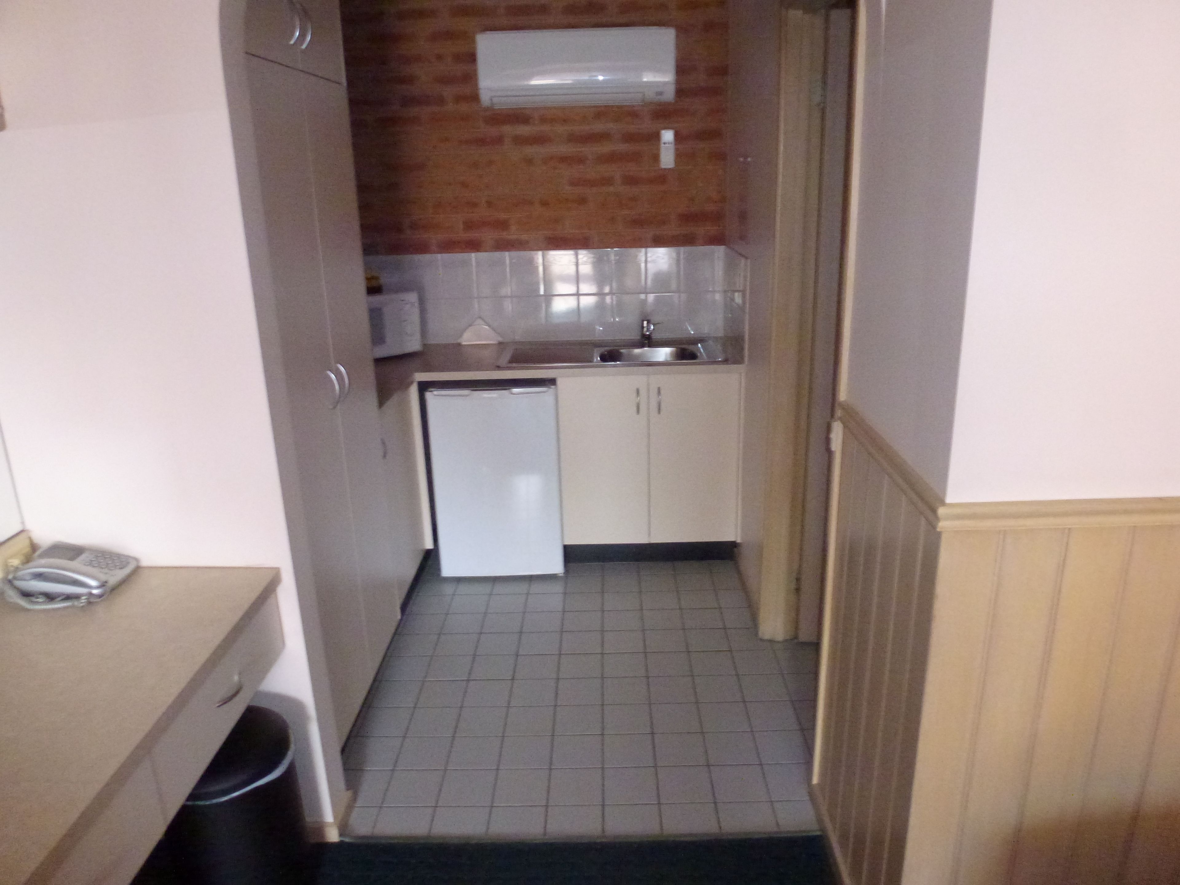 A compact kitchen with a refrigerator, sink, and tiled floor.