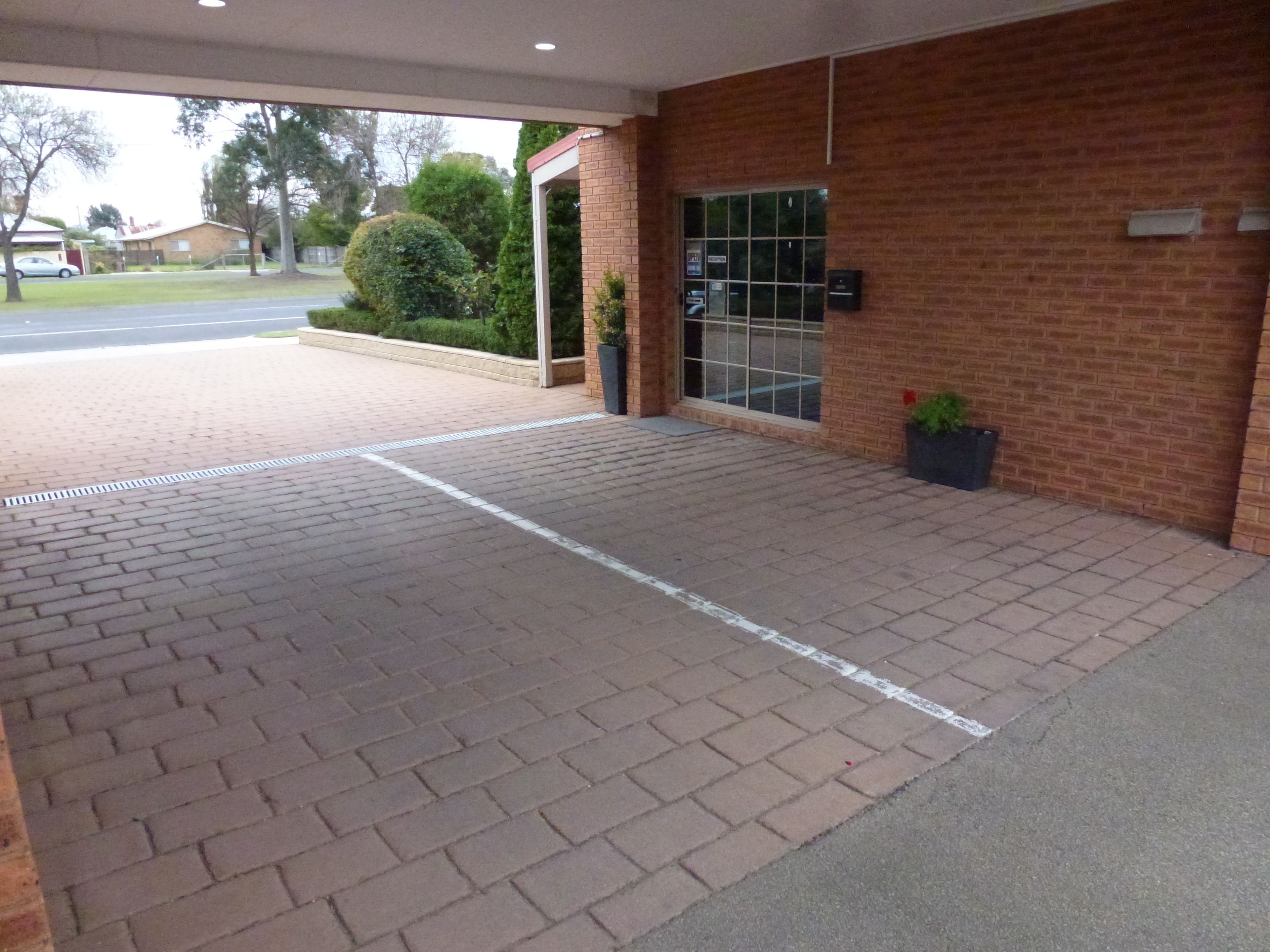 A brick building entrance with a paved walkway leading to a glass door.