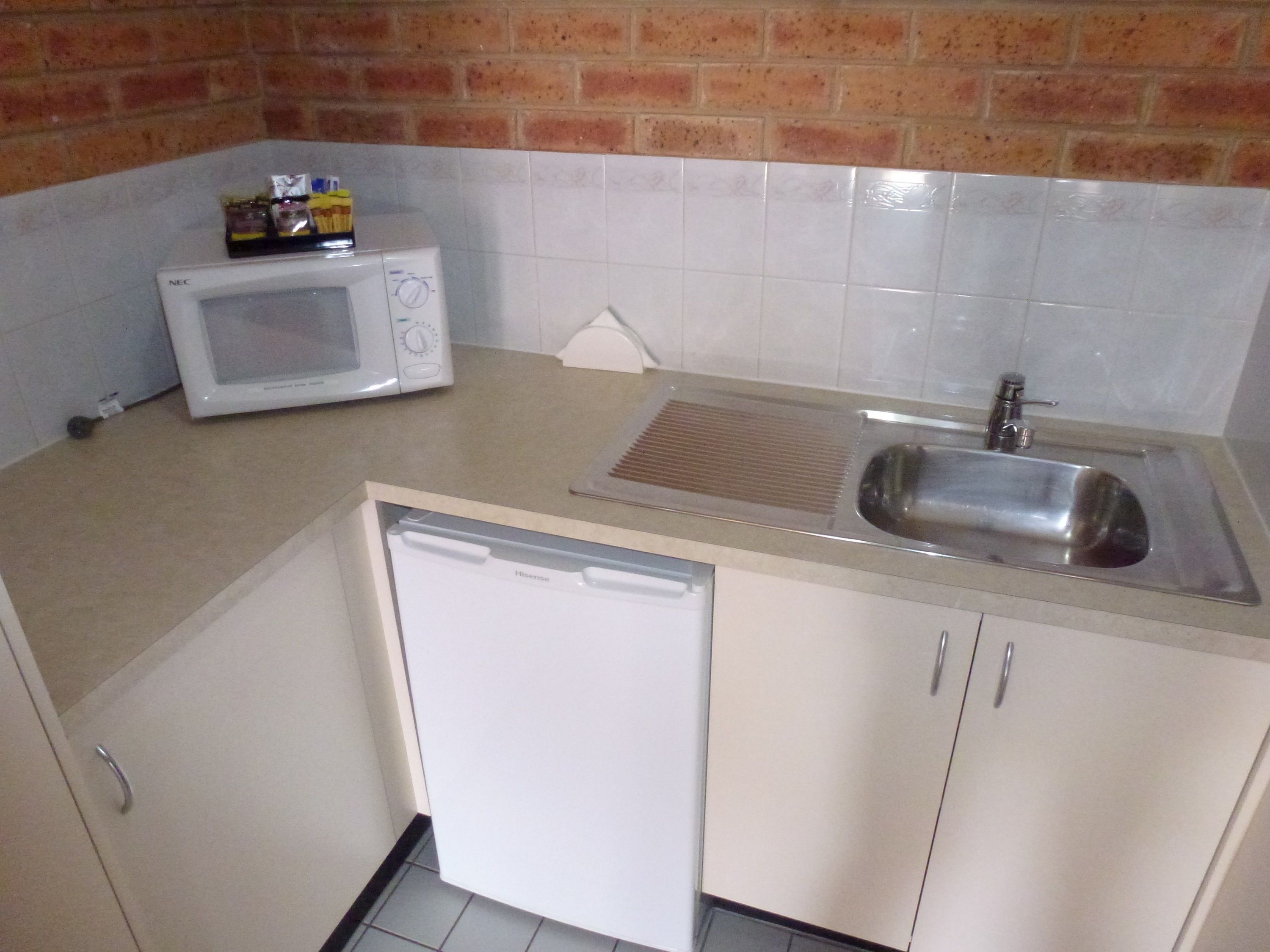 Una cocina compacta equipada con microondas, lavavajillas y fregadero.
