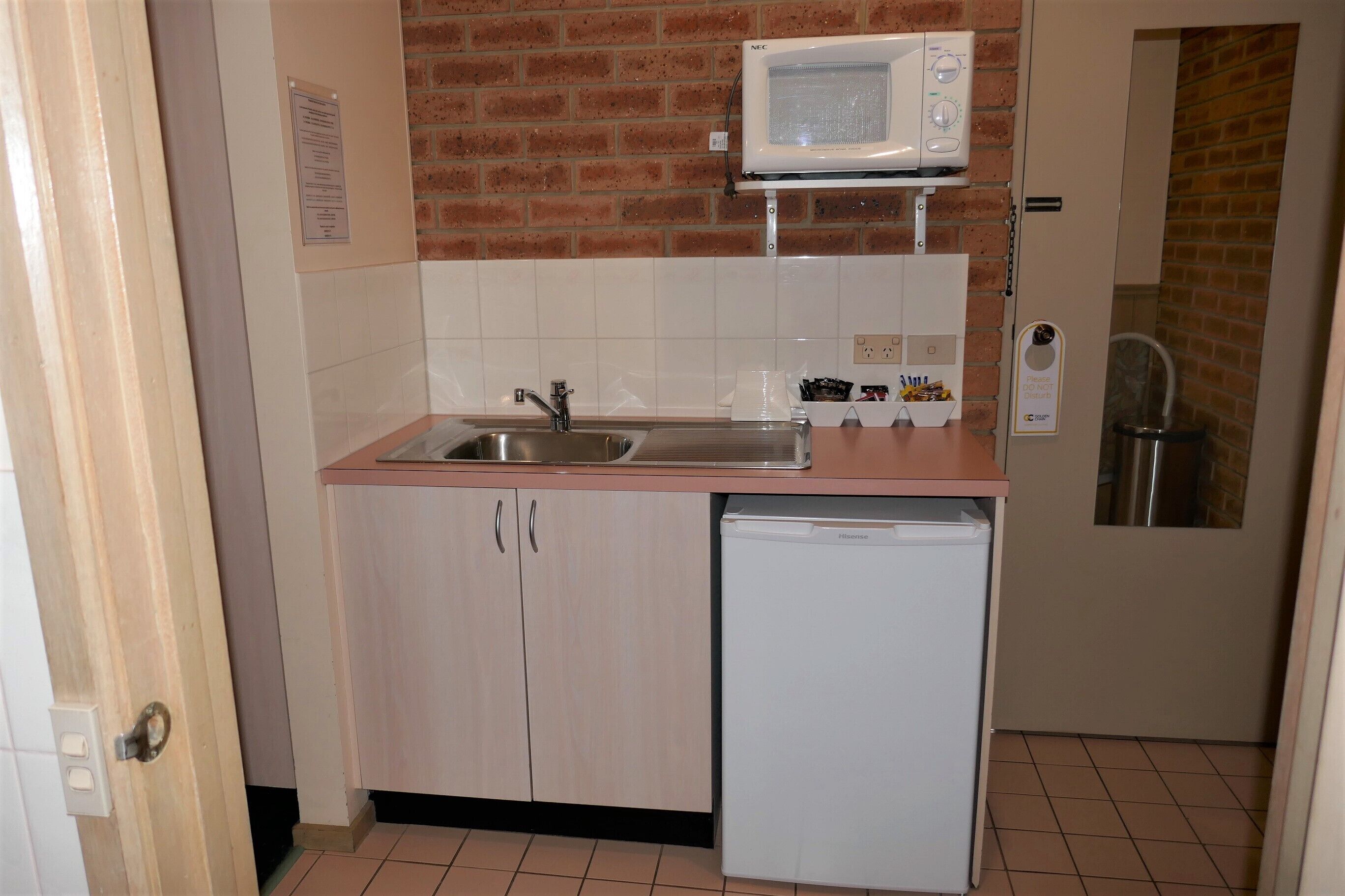 Una cocina compacta con un lavamanos, un microondas y un lavavajillas.