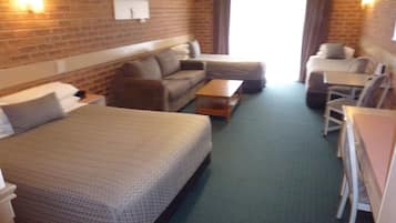 A hotel room with a large bed, a sofa, a small table, and a desk with chairs.