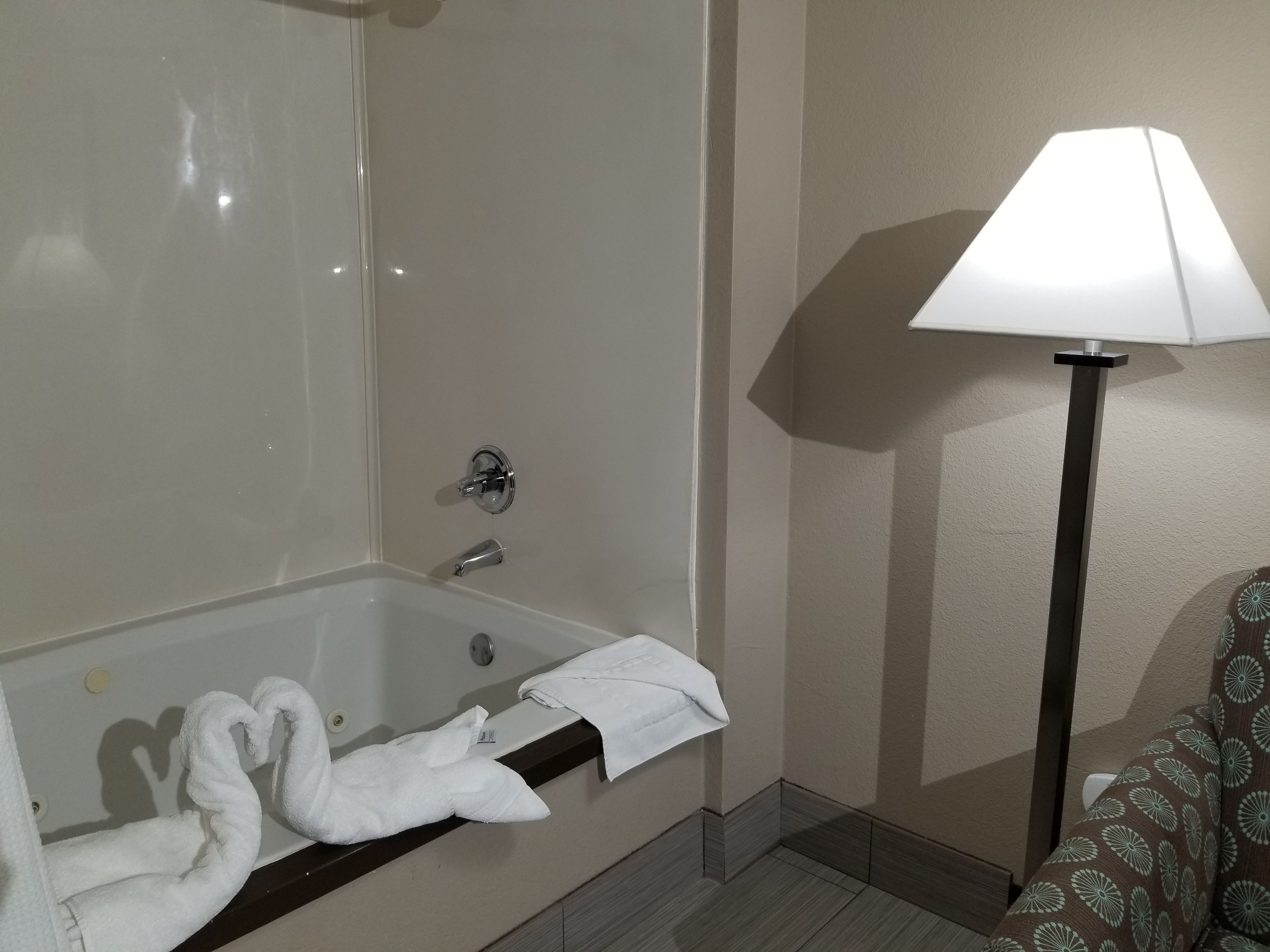 A bathroom with a bathtub, a towel rack, and a floor lamp.