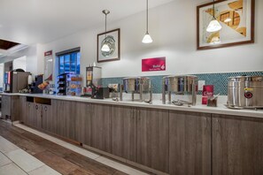 A modern kitchen area with a long counter, various appliances, and a tiled backsplash.