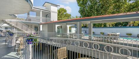 Una terraza en la azotea con piscina, mobiliario exterior y una escalera que lleva a un nivel superior.