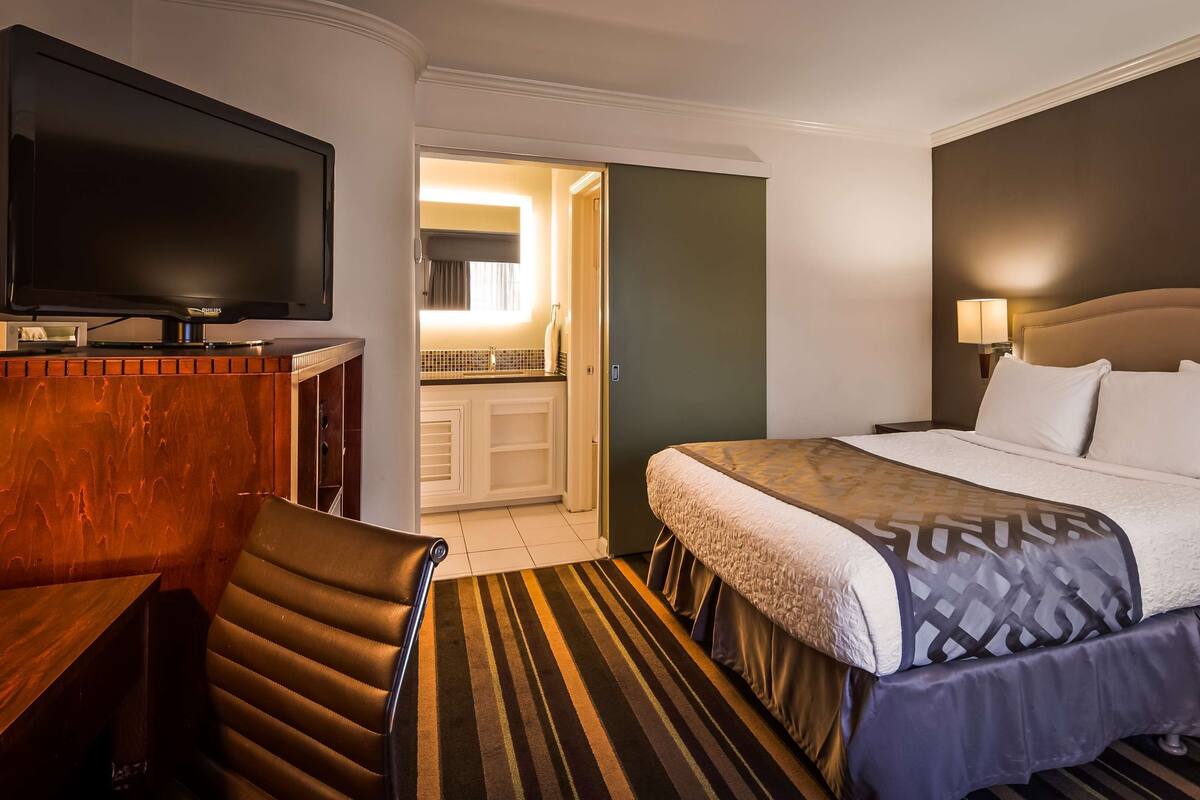 A hotel room with a bed, a television, a desk, and a chair.