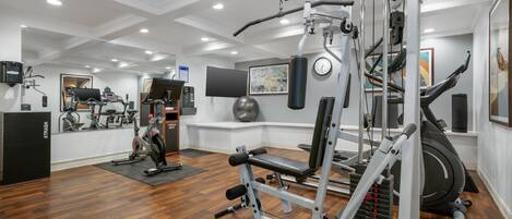 Un gimnasio con diversos equipos de ejercicio, incluyendo una caminadora, bicicletas estáticas y máquinas de pesas.