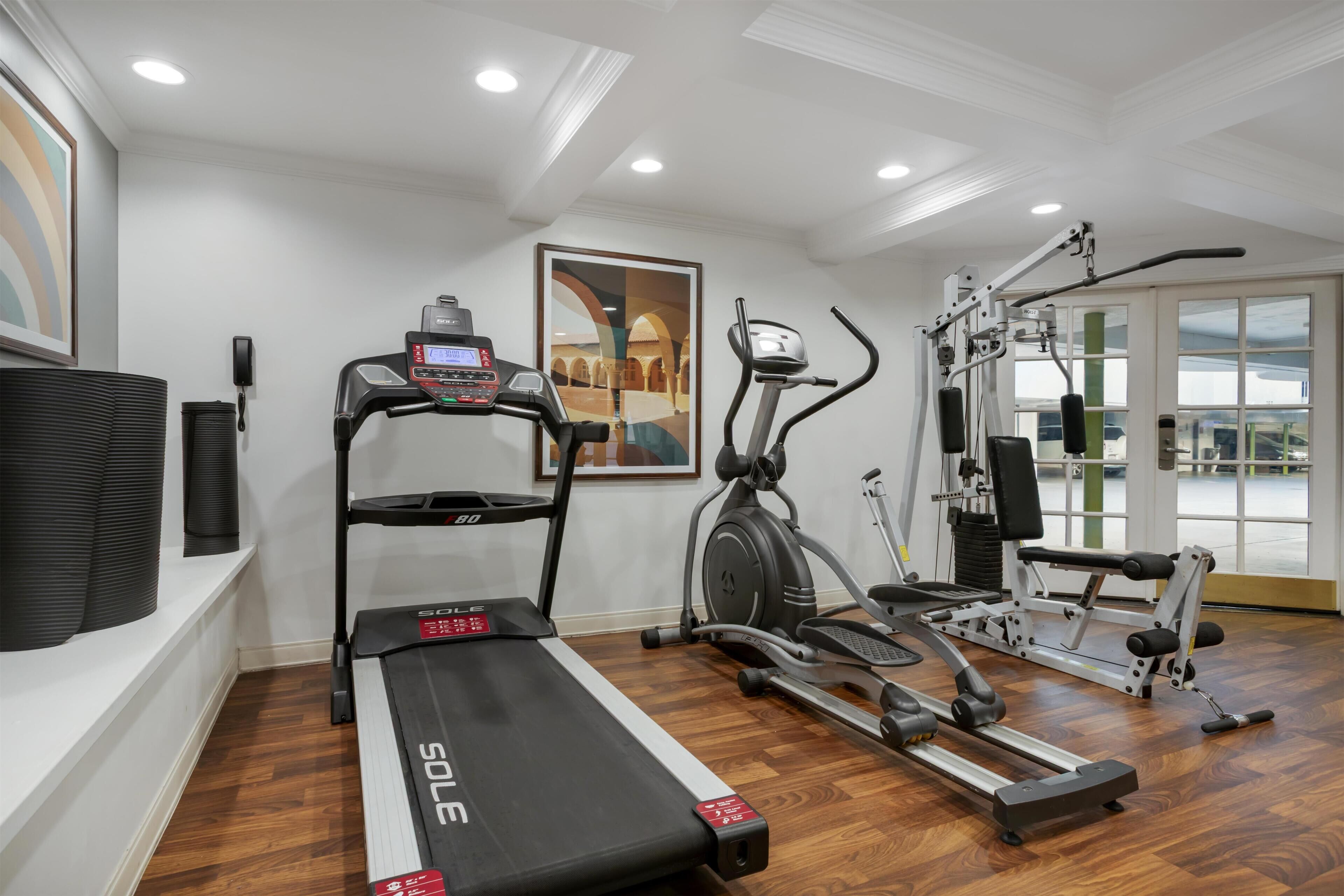 A home gym with a treadmill, elliptical, and weight machines.
