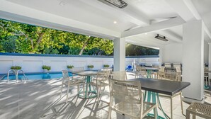 An outdoor patio with a pool, seating area, and a covered section with tables and chairs. - Best Western Plus Riviera (Menlo Park)