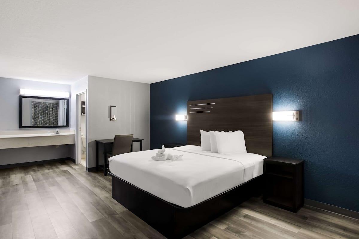 A modern hotel room with a large bed, bedside tables, a desk, and a chair.