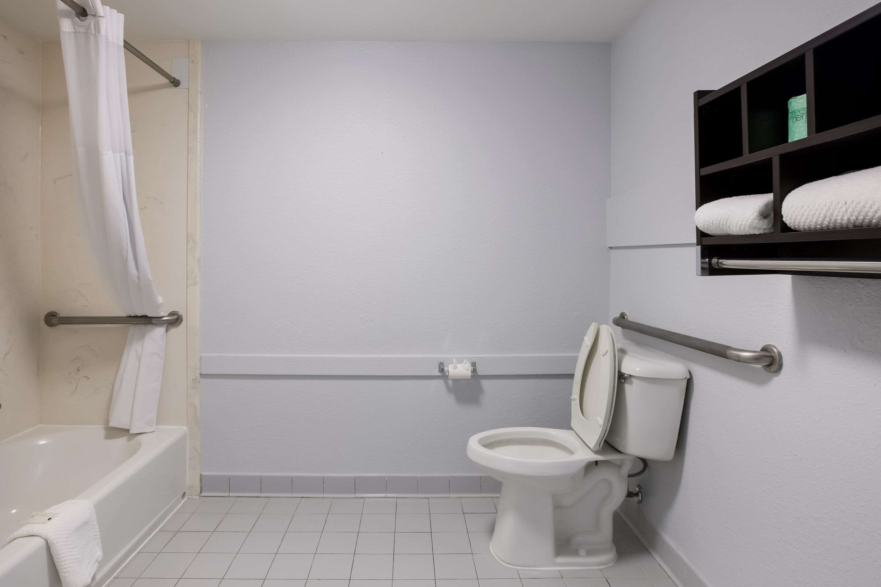 A bathroom with a bathtub, toilet, and a shelf with towels.