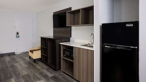 A compact kitchen with a microwave, a sink, and a black refrigerator. - Suburban Studios Hinesville - Fort Stewart Area (Hinesville)