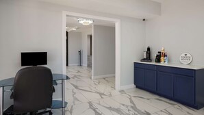 A modern office space with a desk, chair, and a coffee station. - Suburban Studios Hinesville - Fort Stewart Area (Hinesville)