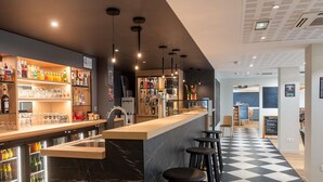 Un espace bar moderne avec un comptoir en marbre, des tabourets noirs et un sol à carreaux.