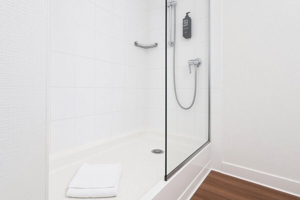 Ducha con cerramiento de vidrio, cabezal de ducha de mano y grifo empotrado.