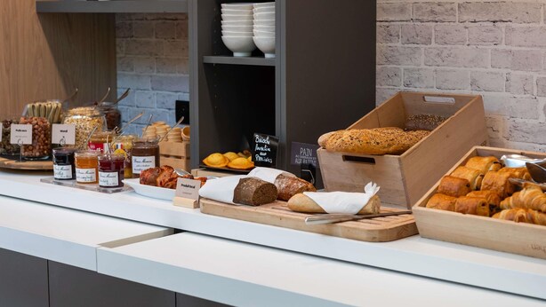 Un buffet de petit-déjeuner proposant une variété d’aliments, notamment du pain, des viennoiseries et des confitures.