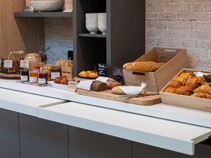 Un buffet de petit-déjeuner proposant une variété d’aliments, notamment du pain, des viennoiseries et des confitures.