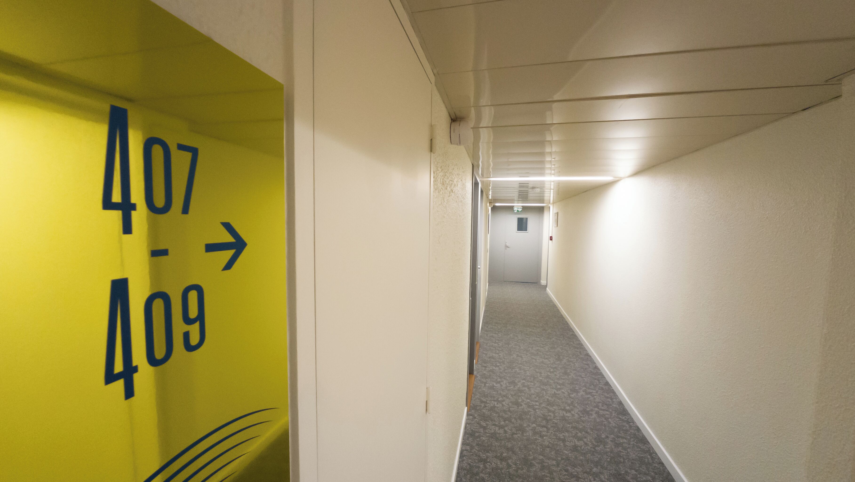 Un pasillo con un cartel indicador de los números de habitación 407 y 409.
