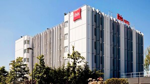 Un hôtel moderne, reconnaissable à son grand panneau « ibis » sur le toit.