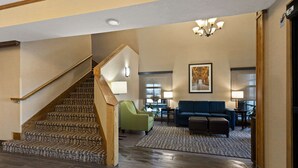 A spacious lobby with a wooden staircase, a blue sofa, and a green armchair. - Comfort Inn Huntington Near University (Huntington)