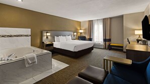 A hotel room with a large bed, a separate bathroom with a bathtub, a desk with a chair, and a bench. - Comfort Inn Huntington Near University (Huntington)