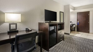A hotel room with a desk, chair, television, refrigerator, and a bathroom visible through an open door. - Best Western Plus Jonesboro Inn and Suites (Jonesboro)
