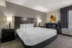 A hotel room with a large bed, two bedside tables with lamps, a flat-screen TV, a coffee machine, and a large window with curtains. - Best Western Plus Jonesboro Inn and Suites (Jonesboro)