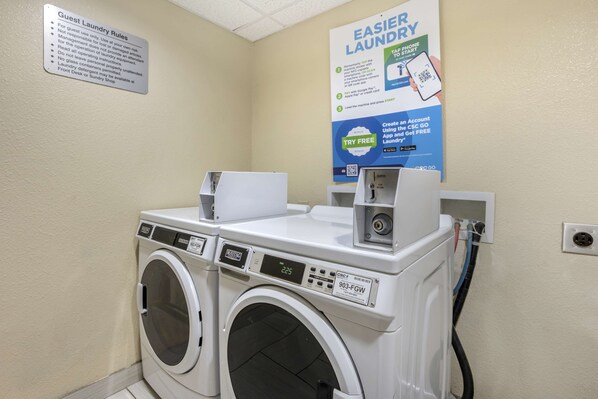 A laundry area with two front-loading washing machines, a sign detailing guest laundry rules, and a poster advertising an app for easier laundry. - Best Western Plus Jonesboro Inn and Suites (Jonesboro)