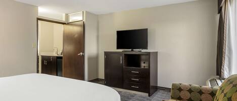 Habitación de hotel con una cama, un televisor sobre un tocador y una silla.