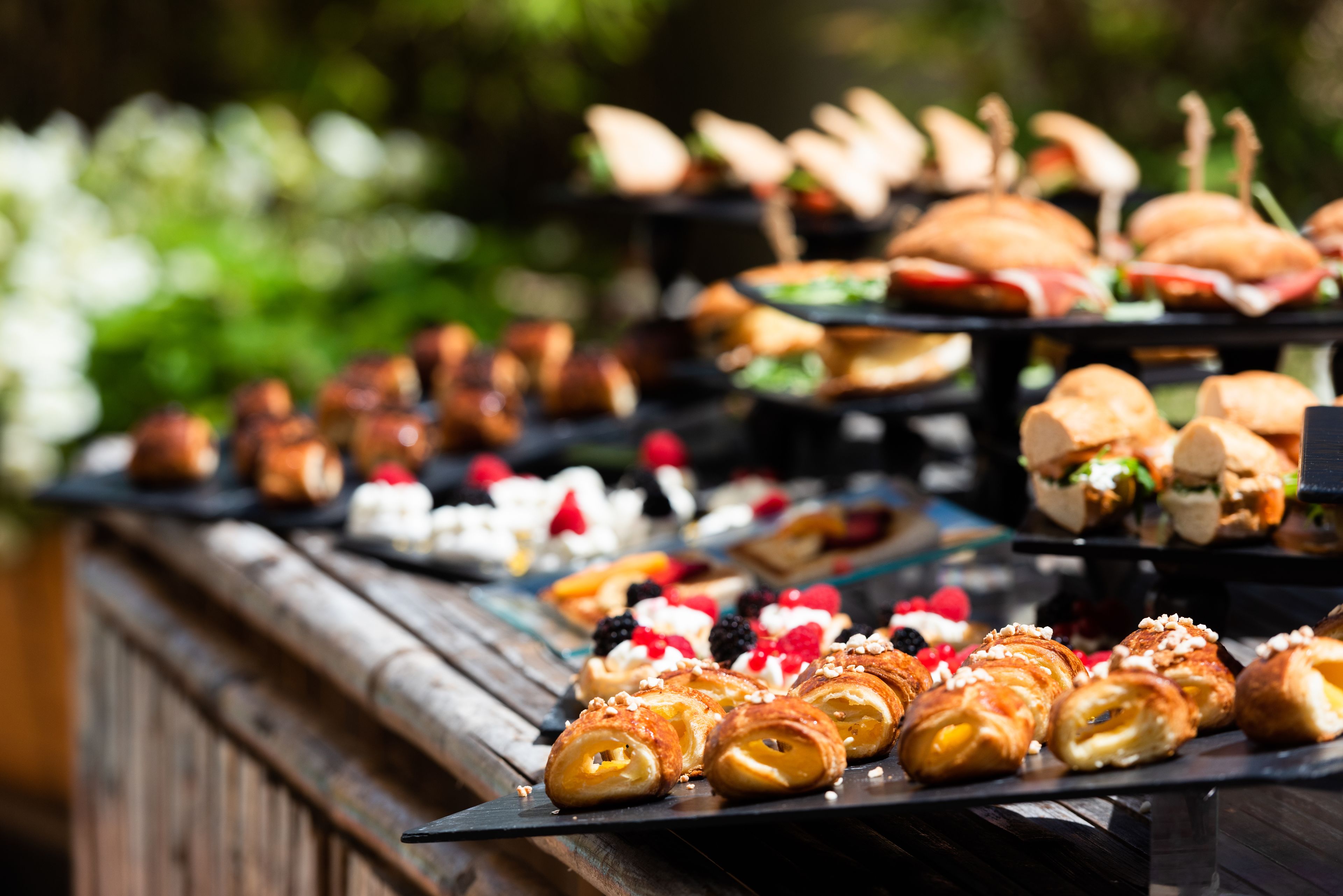 A buffet with various pastries and sandwiches.