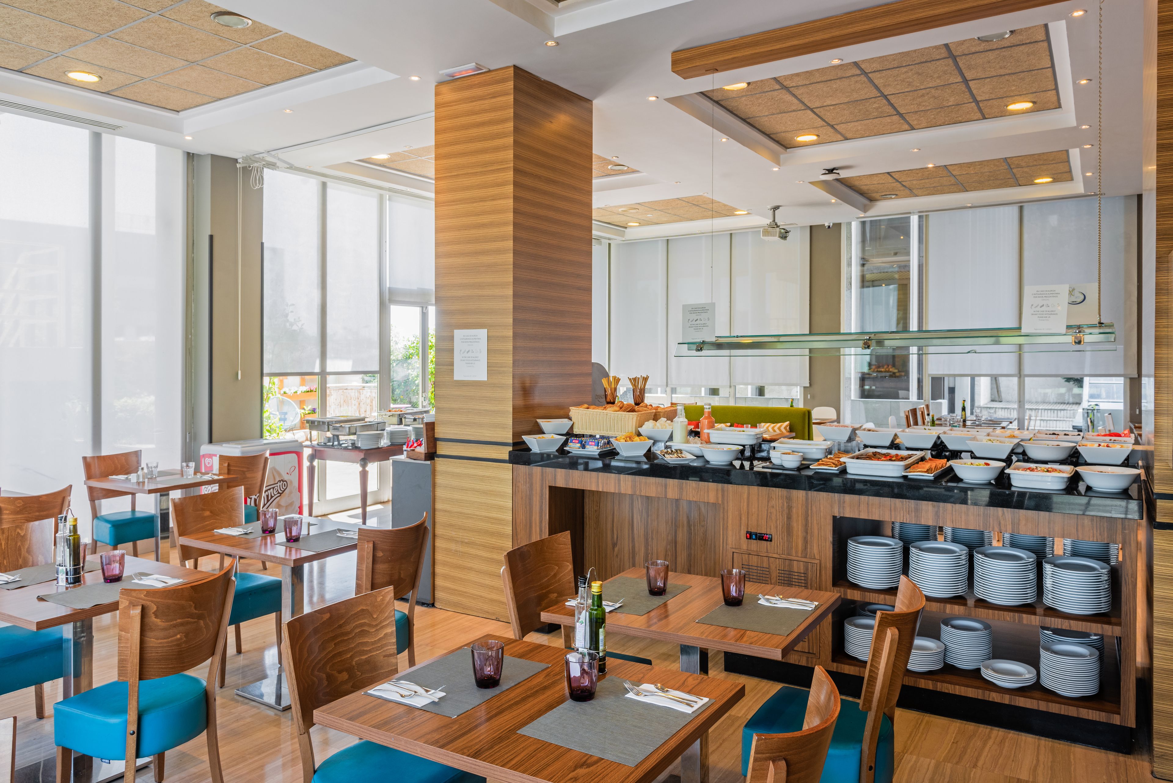Un restaurante moderno con mobiliario de madera, una barra de buffet y una zona de cocina.