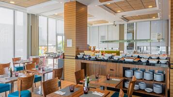 Un restaurante moderno con mobiliario de madera, una barra de buffet y una zona de cocina.