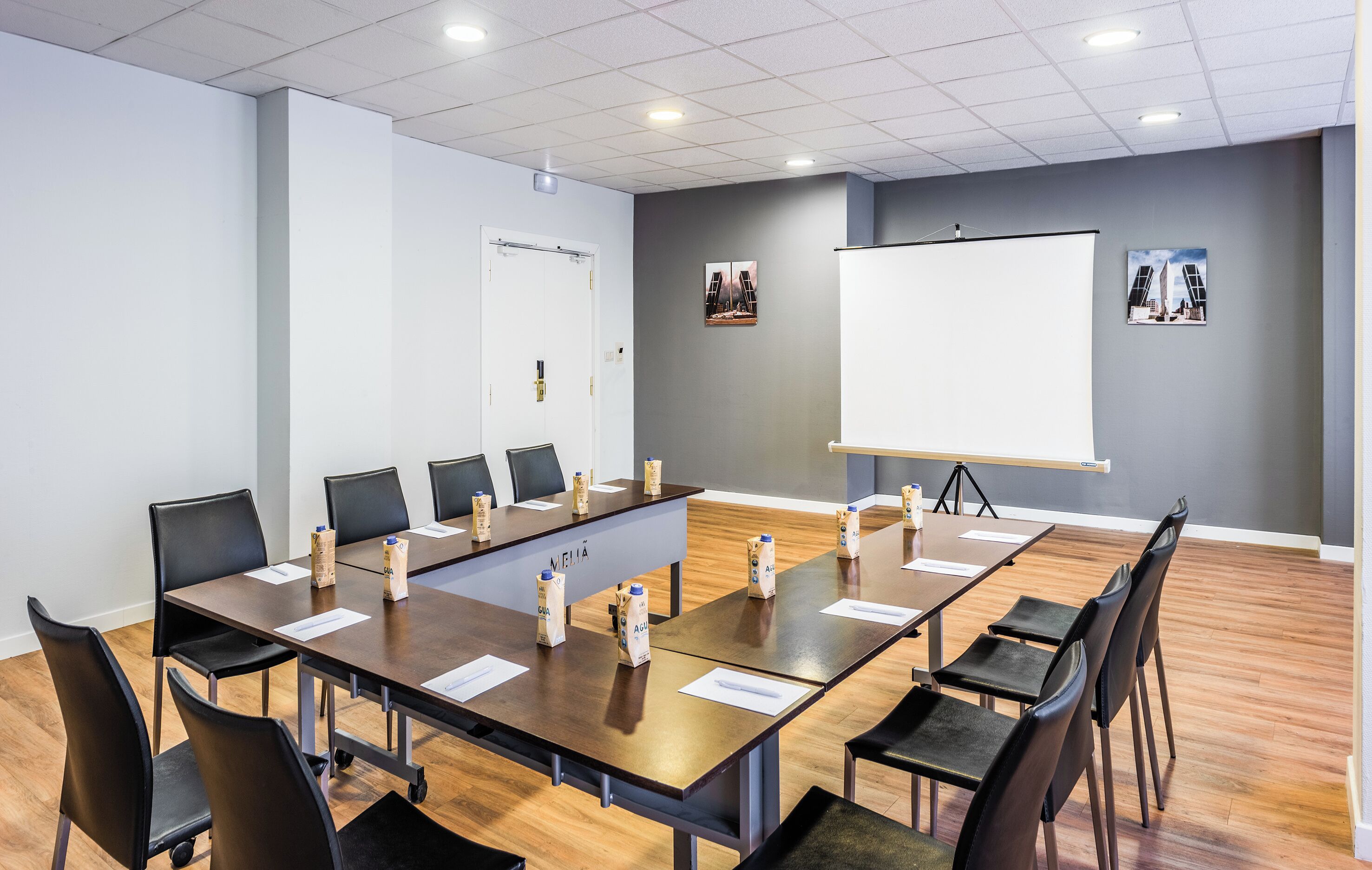 Ein Konferenzraum mit einem langen Tisch, schwarzen Stühlen und einer Whiteboard-Tafel.