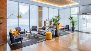 A modern lobby with a sofa, chairs, a coffee table, and a large window. - Hotel Madrid Chamartín Affiliated by Meliá (Madrid)