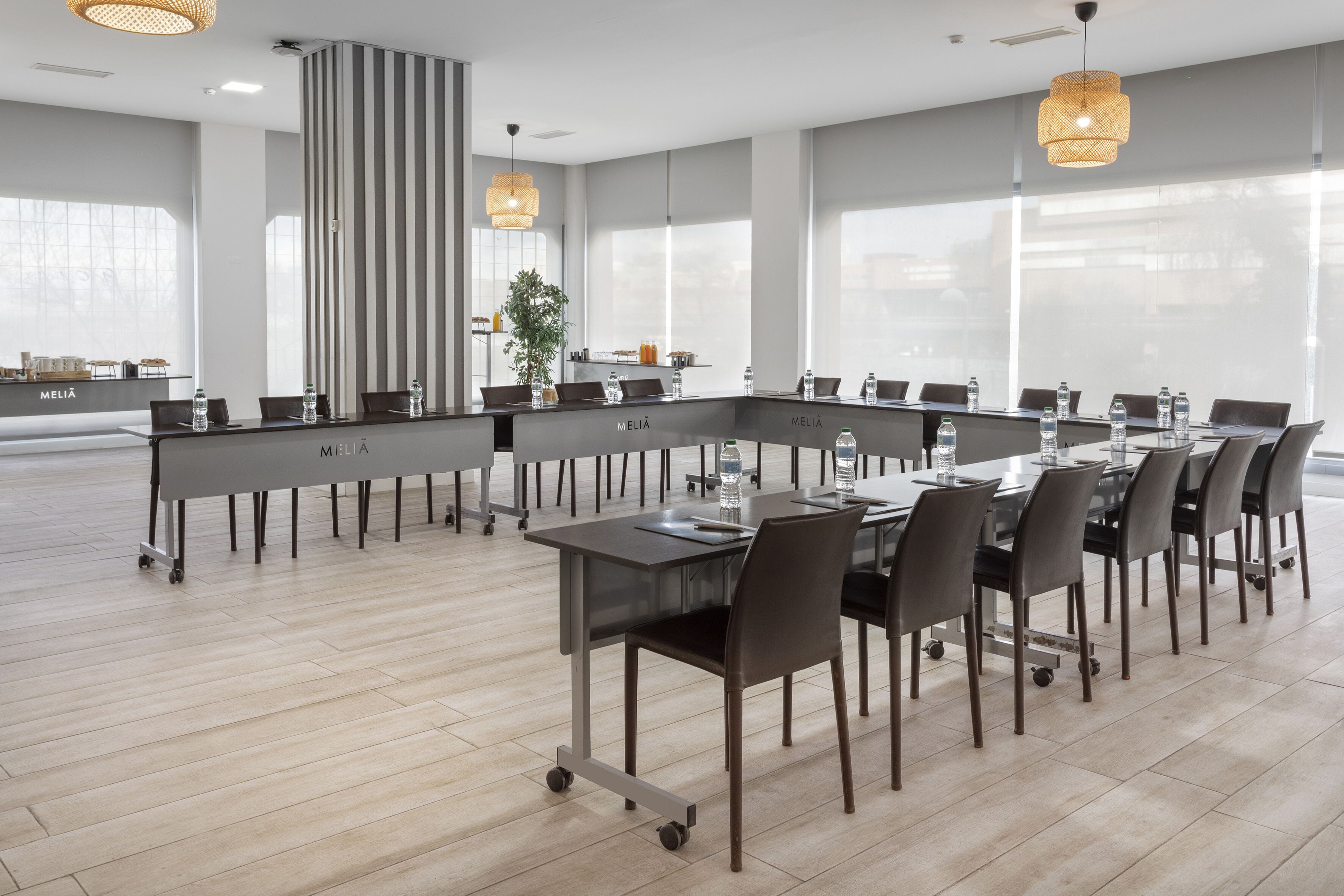 A conference room with a long table, chairs, water bottles, and a plant.