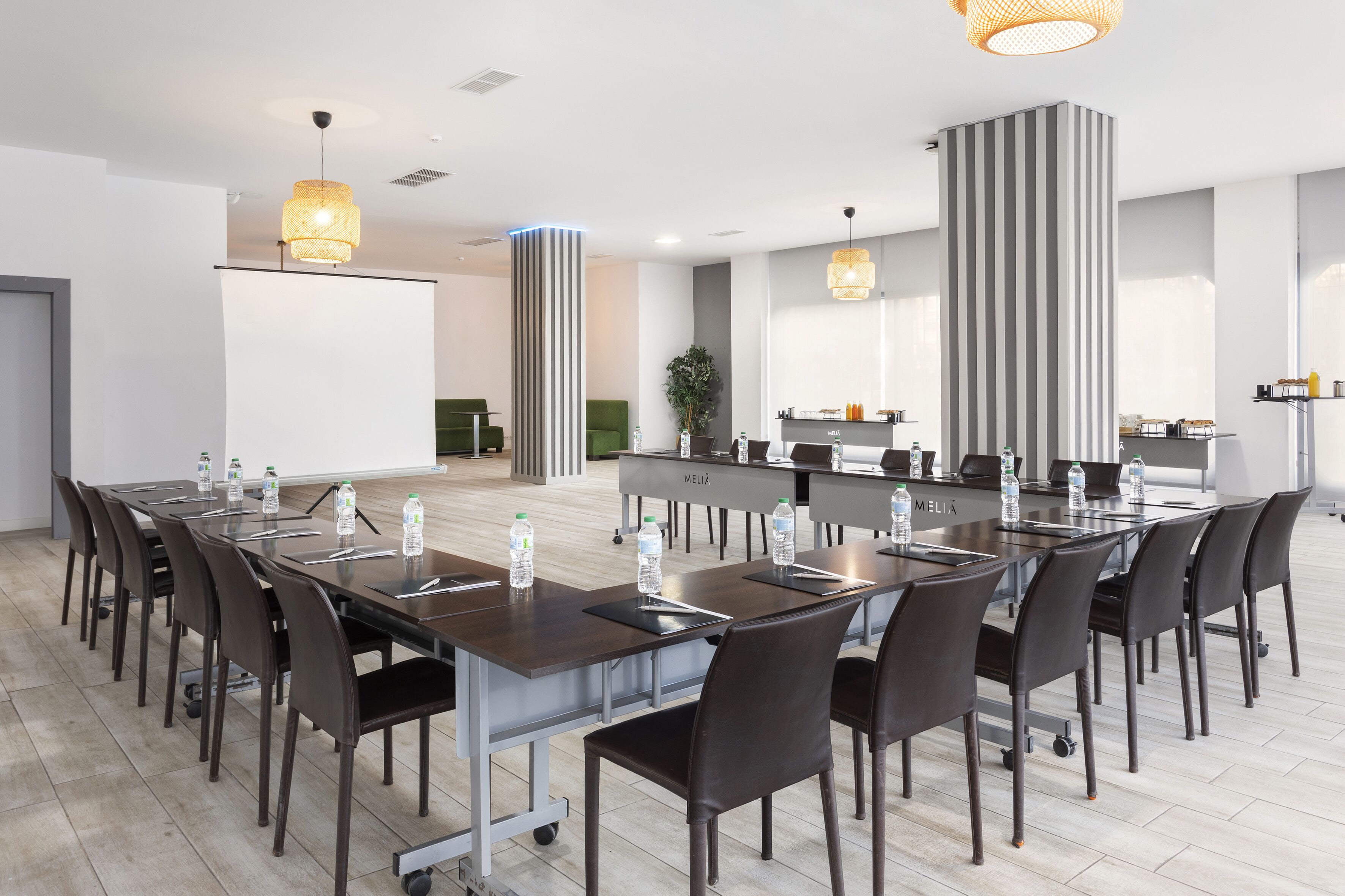 A modern conference room with a long table, chairs, and water bottles.