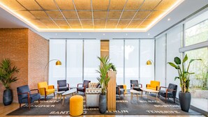 A modern lobby with a brick wall, large windows, and seating areas with a city-themed rug. - Hotel Madrid Chamartín Affiliated by Meliá (Madrid)
