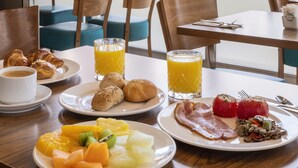 A breakfast setting with a table, chairs, and a view of tall buildings. - Hotel Madrid Chamartín Affiliated by Meliá (Madrid)