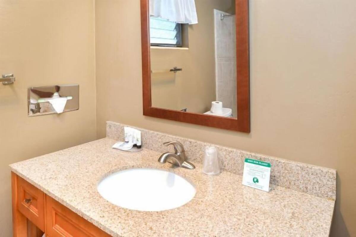A bathroom with a granite countertop, a white sink, a mirror, and a towel rack.