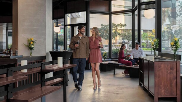 Un intérieur moderne avec des bancs en bois, un comptoir d’accueil et de grandes fenêtres donnant sur la ville.