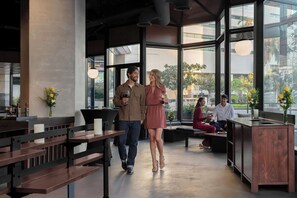 Un interior moderno con bancos de madera, una mesa de recepción y grandes ventanales con vistas a la ciudad.