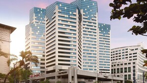 Un hôtel à plusieurs étages, caractérisé par une architecture verticale imposante, avec une façade combinant des éléments en verre et en béton.