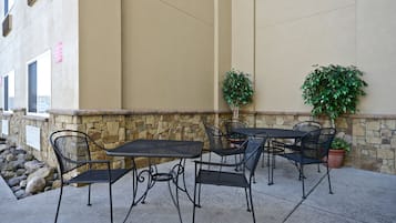 An outdoor patio with a stone wall, a table, and chairs.