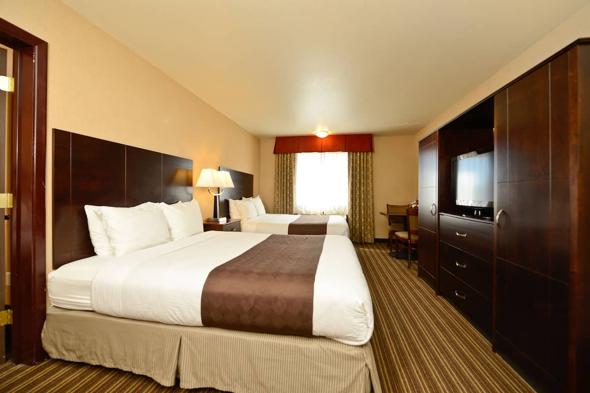 A hotel room with two beds, a TV, a desk, and a chair.