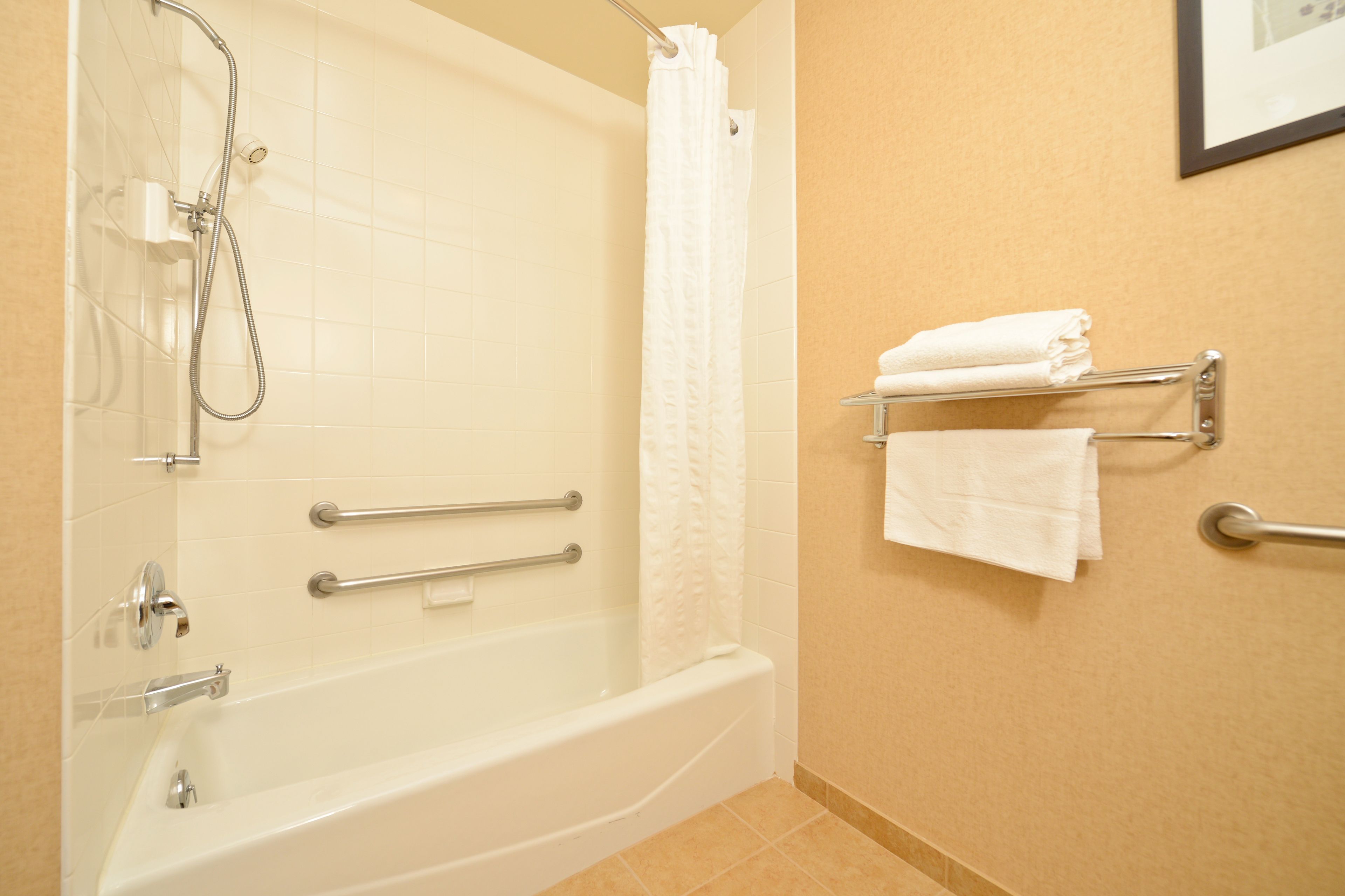 A bathroom with a bathtub, shower, and towel rack.