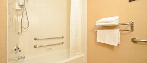 A bathroom with a bathtub, shower, and towel rack.