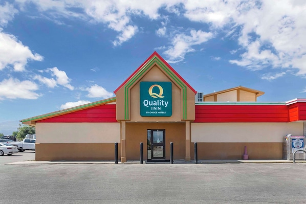 A Quality Inn by Choice Hotels building with a red and green roof, beige walls, and a clear blue sky. - Quality Inn Hamilton Bitterroot Valley (Hamilton)